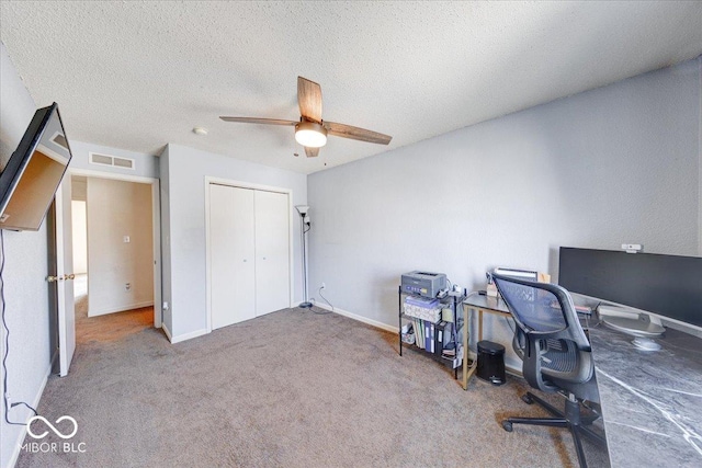 office space featuring a ceiling fan, baseboards, visible vents, carpet floors, and a textured ceiling