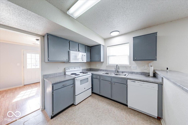 kitchen featuring a sink, white appliances, light floors, and plenty of natural light