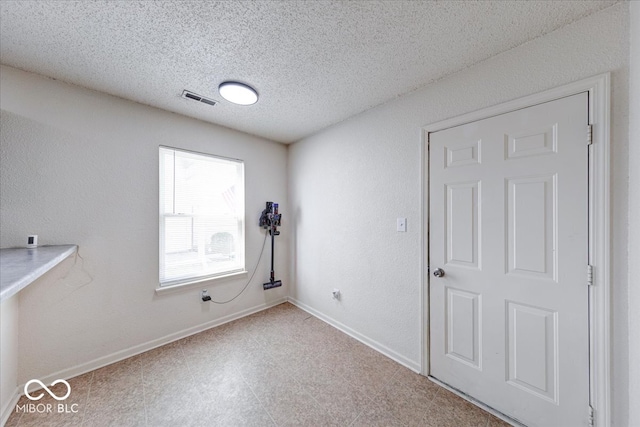 unfurnished room featuring visible vents, baseboards, a textured ceiling, and a textured wall