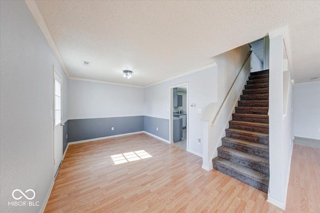 interior space with visible vents, crown molding, stairway, light wood-style floors, and a textured ceiling