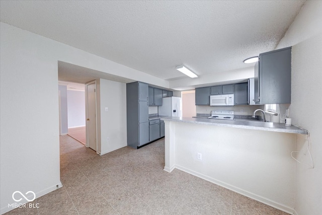 kitchen featuring light countertops, a peninsula, white appliances, a textured ceiling, and a sink