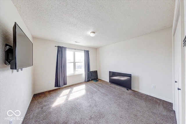 empty room with baseboards, a textured ceiling, and carpet