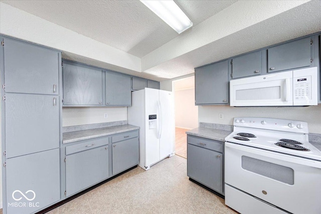 kitchen with white appliances, light countertops, light floors, and a textured ceiling