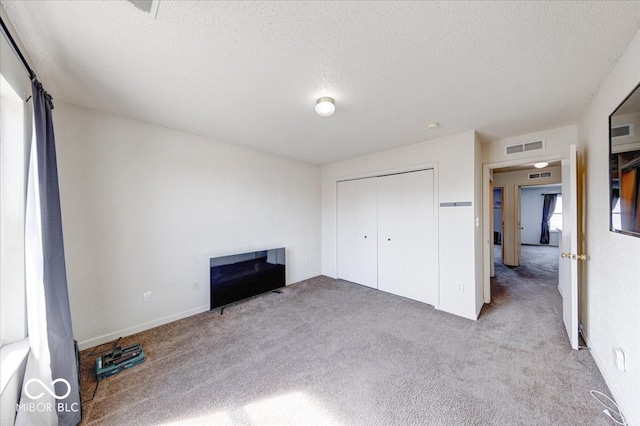 unfurnished bedroom featuring visible vents, carpet, a fireplace, and a textured ceiling