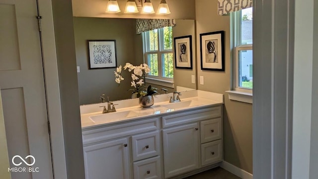 bathroom featuring a sink, baseboards, and double vanity