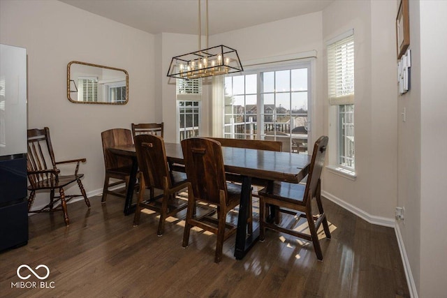 dining space with baseboards, a chandelier, and dark wood-style flooring