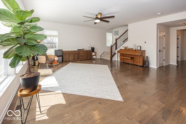 interior space featuring dark wood-type flooring, stairway, baseboards, and ceiling fan