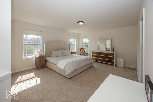 carpeted bedroom featuring multiple windows and baseboards