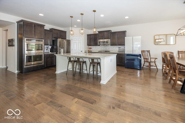 kitchen featuring light countertops, dark brown cabinets, tasteful backsplash, and stainless steel appliances