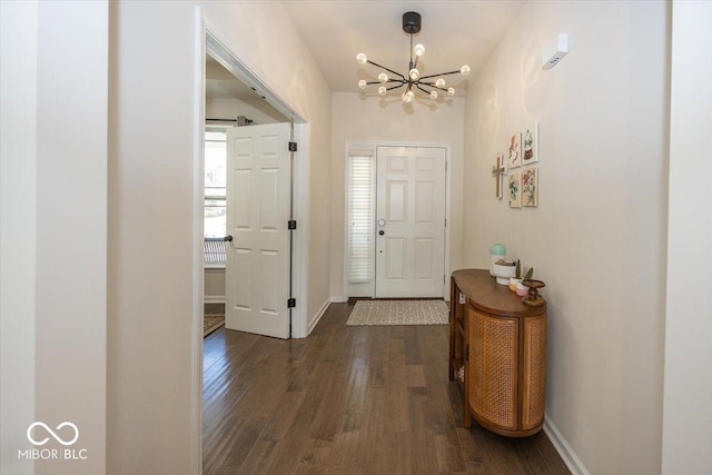 entryway featuring dark wood-type flooring, baseboards, and a chandelier