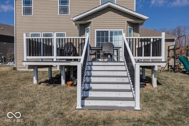 rear view of house featuring stairs, a deck, a yard, and a playground