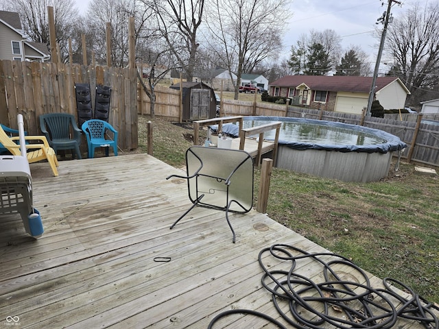 wooden deck with a shed, a fenced in pool, an outdoor structure, and a fenced backyard