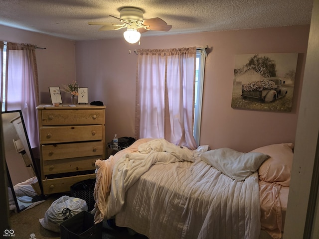 carpeted bedroom featuring multiple windows, a textured ceiling, and a ceiling fan