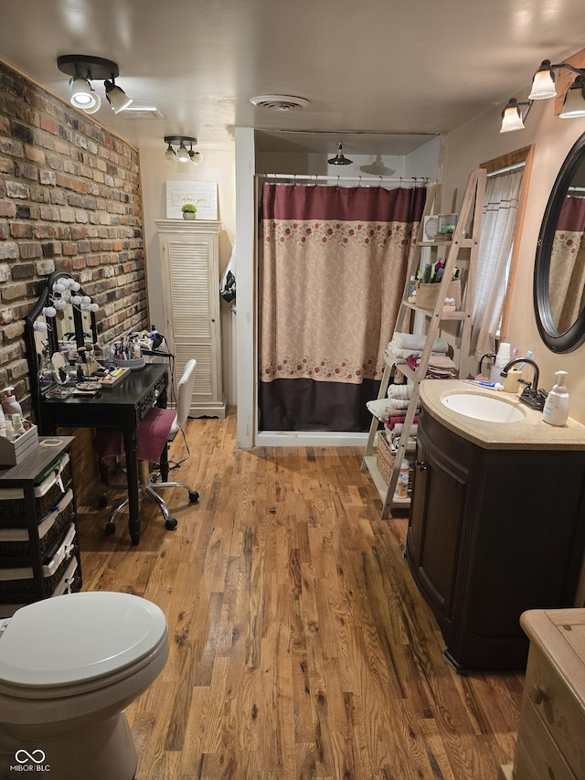 full bathroom featuring visible vents, wood finished floors, a shower with shower curtain, brick wall, and vanity