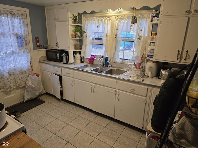 kitchen featuring open shelves, black microwave, light countertops, white cabinets, and a sink