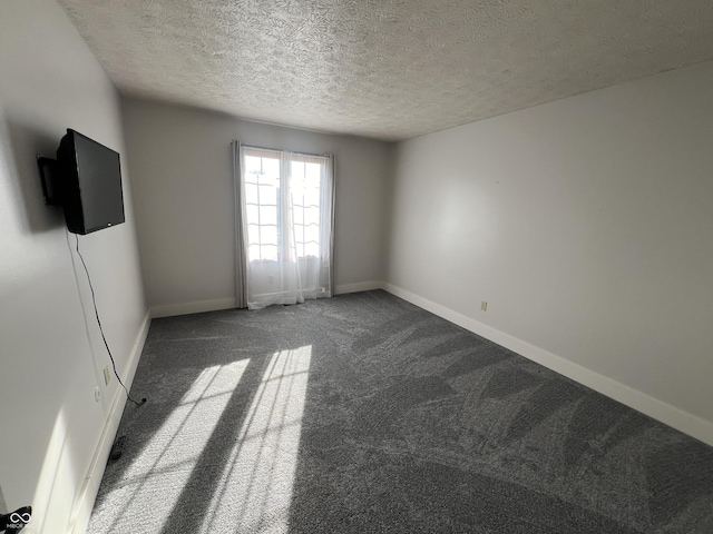 carpeted spare room featuring baseboards and a textured ceiling