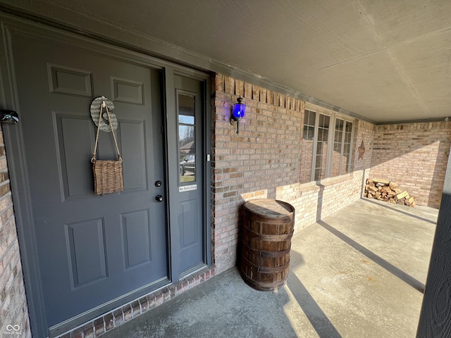 property entrance with brick siding and a porch