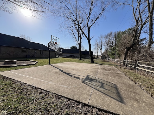 view of basketball court featuring basketball hoop, a yard, and fence