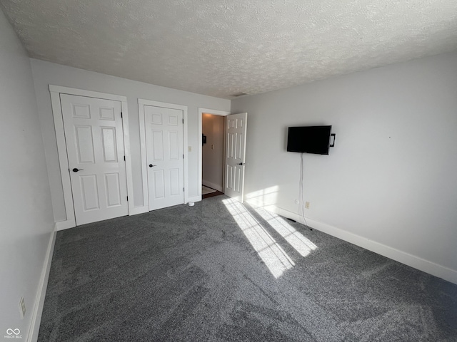 unfurnished bedroom featuring carpet flooring, a textured ceiling, and baseboards