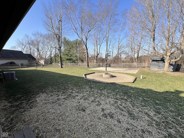 view of yard with an outbuilding, central AC unit, and fence