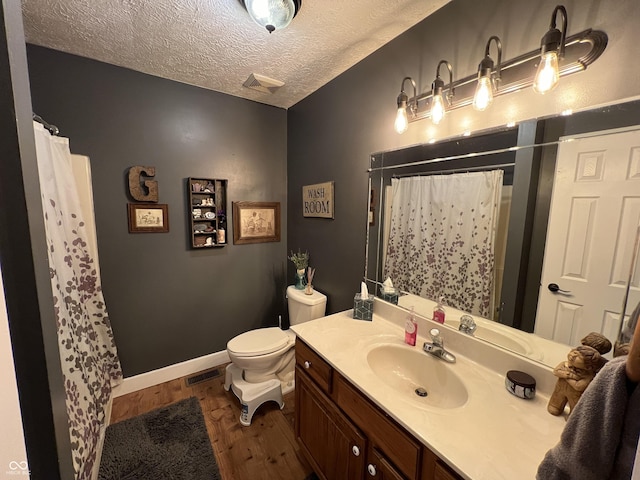 full bath featuring vanity, wood finished floors, visible vents, and a textured ceiling