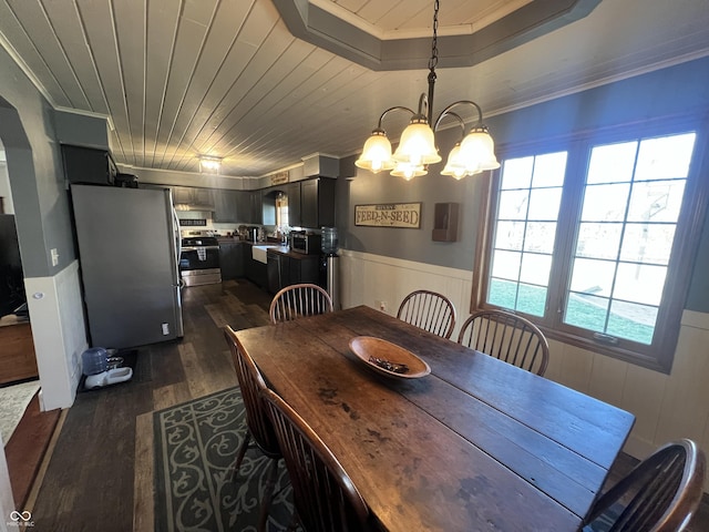 dining area with a chandelier, a wainscoted wall, dark wood finished floors, wood ceiling, and ornamental molding