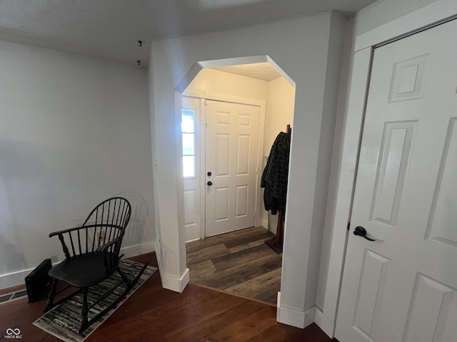 foyer featuring visible vents, wood finished floors, arched walkways, and baseboards