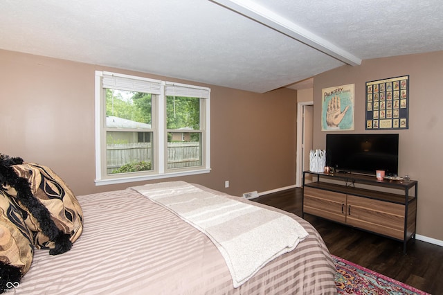 bedroom featuring vaulted ceiling with beams, wood finished floors, baseboards, and a textured ceiling