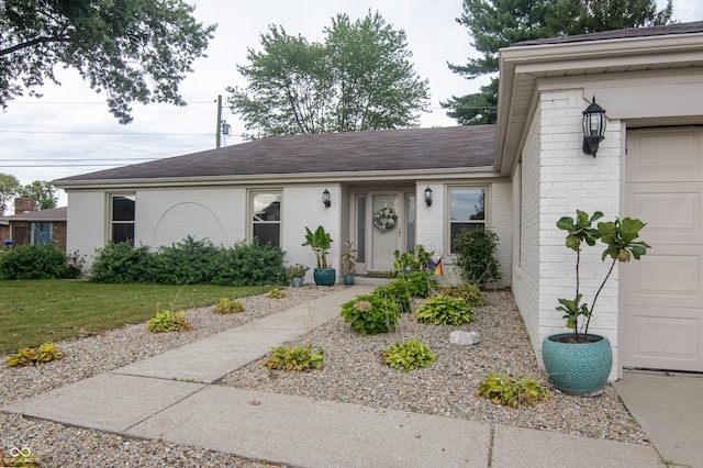 single story home with brick siding, an attached garage, a shingled roof, and a front lawn