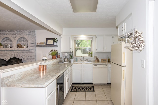 kitchen featuring light countertops, light tile patterned floors, a peninsula, white appliances, and white cabinetry