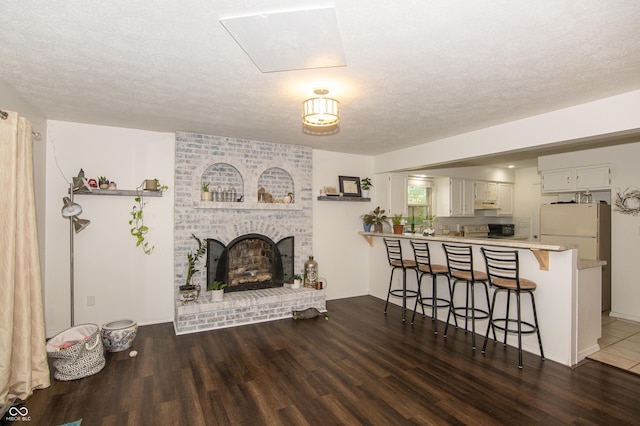 living room featuring a fireplace, a textured ceiling, and wood finished floors