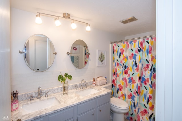 full bathroom with a sink, visible vents, toilet, and double vanity