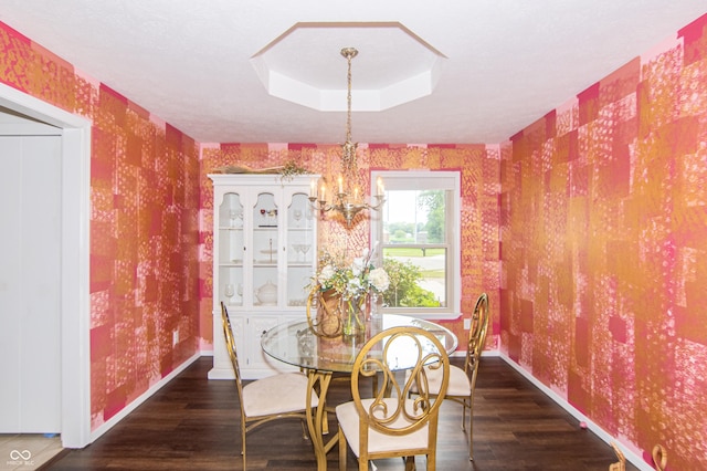 dining area featuring wallpapered walls, baseboards, a chandelier, wood finished floors, and a raised ceiling