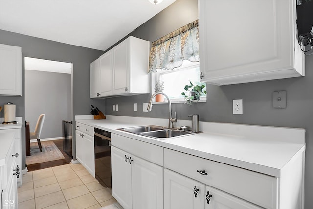 kitchen with light tile patterned floors, white cabinets, black dishwasher, and a sink