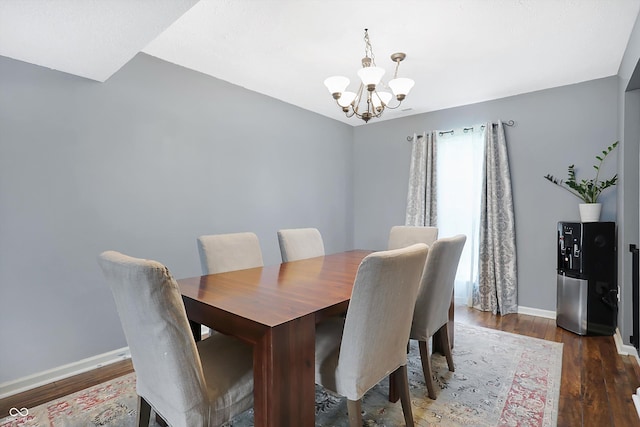 dining space featuring baseboards, a notable chandelier, and wood finished floors