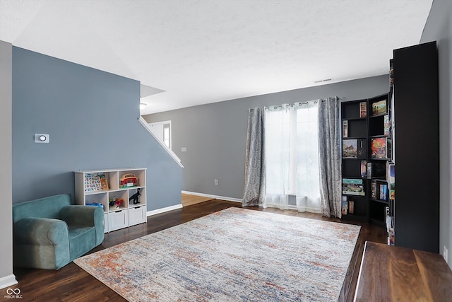 living area with visible vents, dark wood-style floors, baseboards, and a textured ceiling