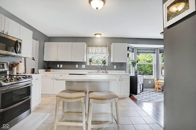 kitchen with light tile patterned floors, appliances with stainless steel finishes, light countertops, and a sink