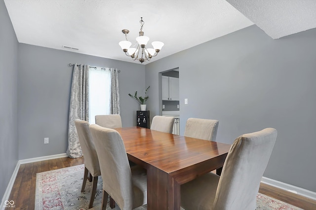 dining area with visible vents, wood finished floors, baseboards, and a chandelier