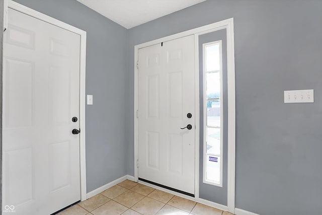 foyer entrance with a wealth of natural light, baseboards, and light tile patterned flooring