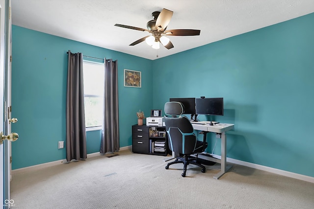 carpeted office space featuring baseboards and ceiling fan