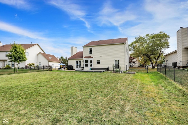 rear view of house featuring a lawn and a fenced backyard