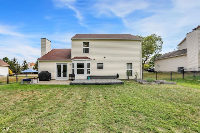 rear view of property with french doors, a lawn, a fenced backyard, and a wooden deck