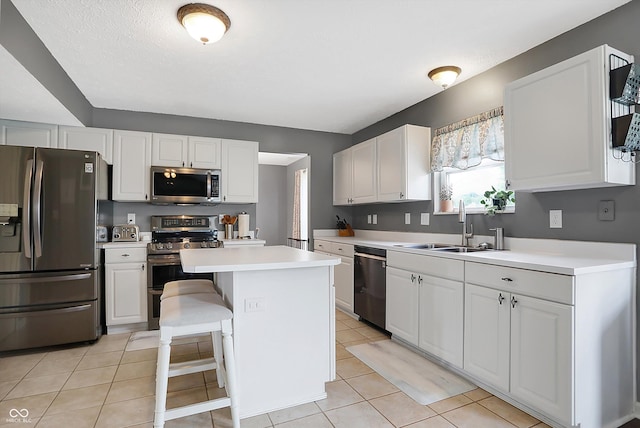 kitchen featuring a sink, appliances with stainless steel finishes, white cabinets, light tile patterned flooring, and light countertops