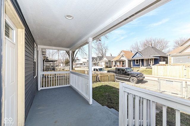 view of patio / terrace featuring a residential view, covered porch, and fence