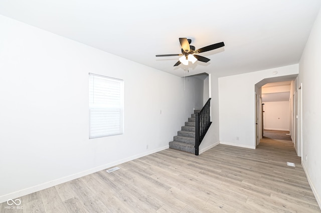 unfurnished living room with stairway, light wood-style flooring, visible vents, and baseboards