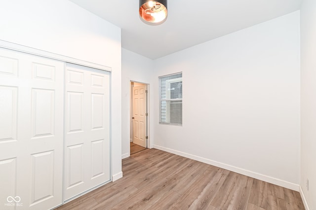 unfurnished bedroom featuring a closet, baseboards, and light wood finished floors