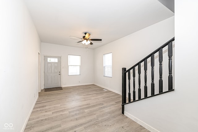 entrance foyer with stairway, a ceiling fan, light wood-type flooring, and baseboards