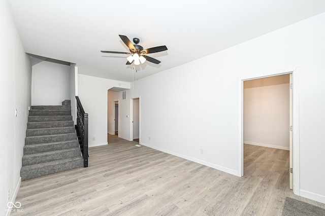 interior space with visible vents, light wood-style flooring, a ceiling fan, baseboards, and stairs