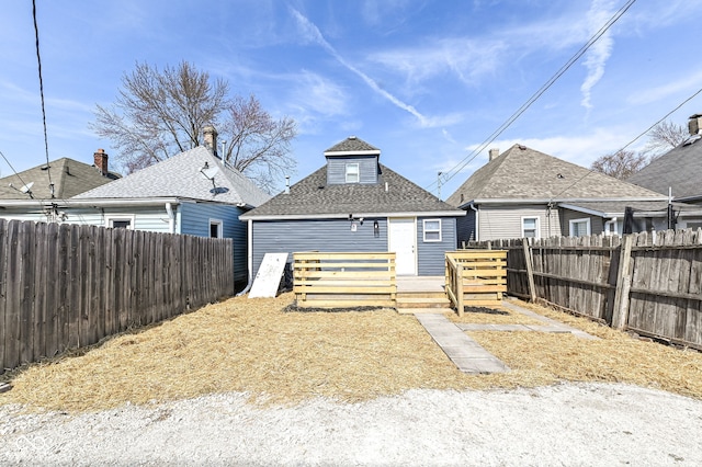 rear view of property featuring a fenced backyard, roof with shingles, and a wooden deck