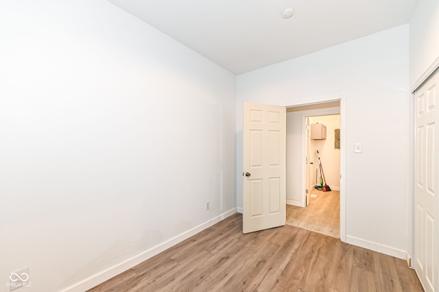 unfurnished bedroom featuring light wood-style flooring, baseboards, and a closet